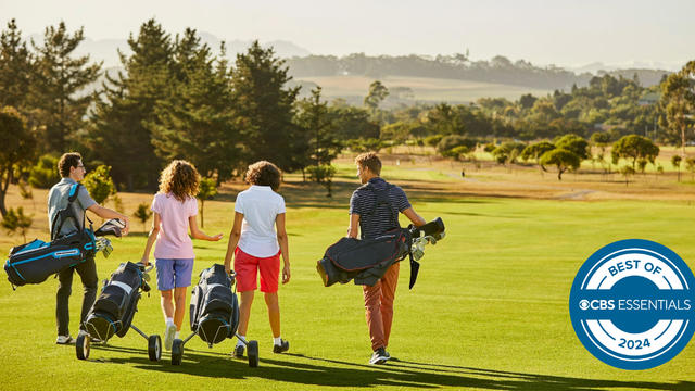 Friends at golf course against sky on sunny day 