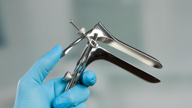 close up of a speculum in front of a clinic room 