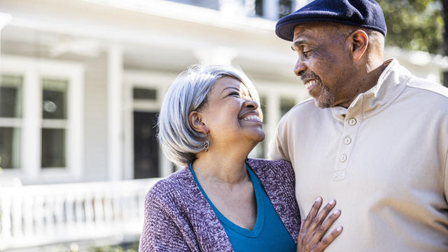 Portrait of senior couple in front of suburban home 