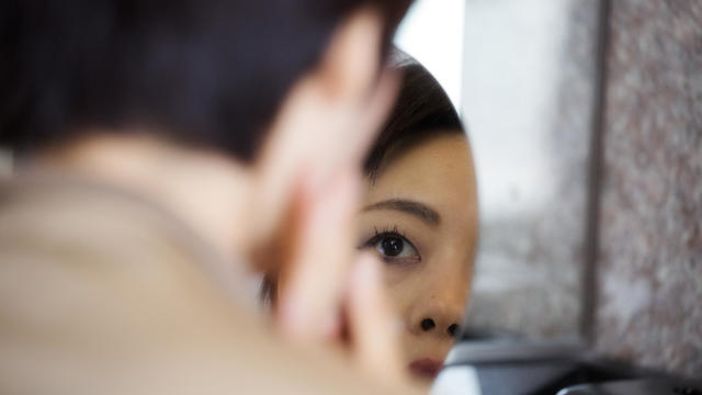 Young African woman examining her skin in a bathroom mirror 