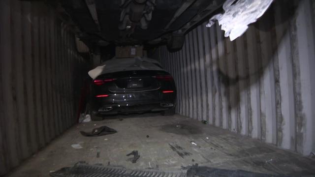 A Mercedes sedan in the back of a shipping container. 